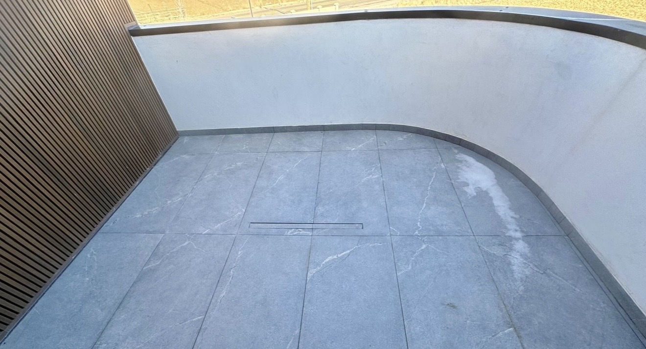 Curved outdoor balcony with large gray tile