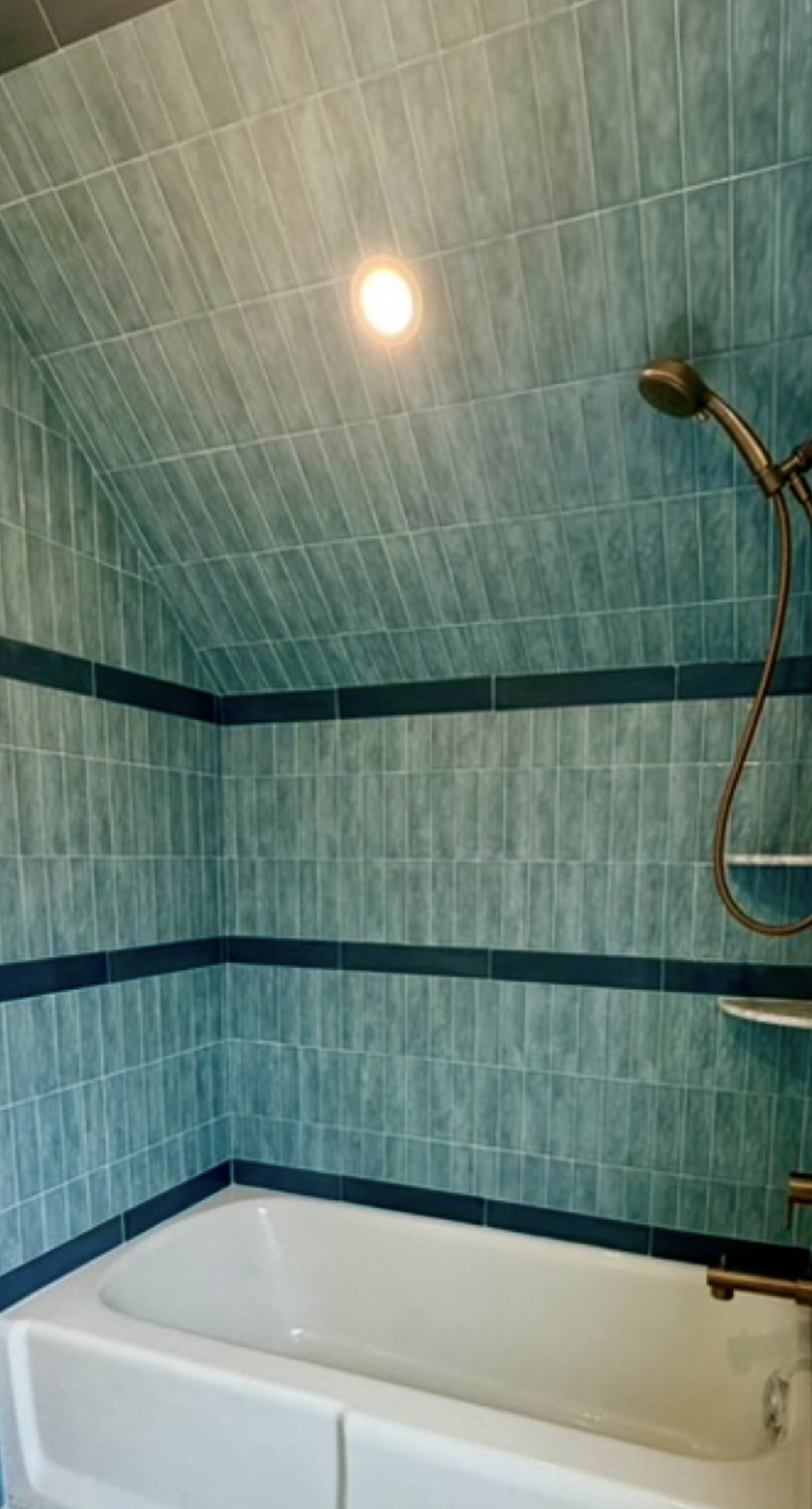 Green tiled bathtub surround with dark accent bands